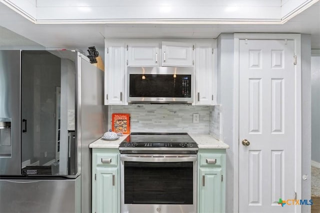 kitchen featuring stainless steel appliances, white cabinetry, and backsplash