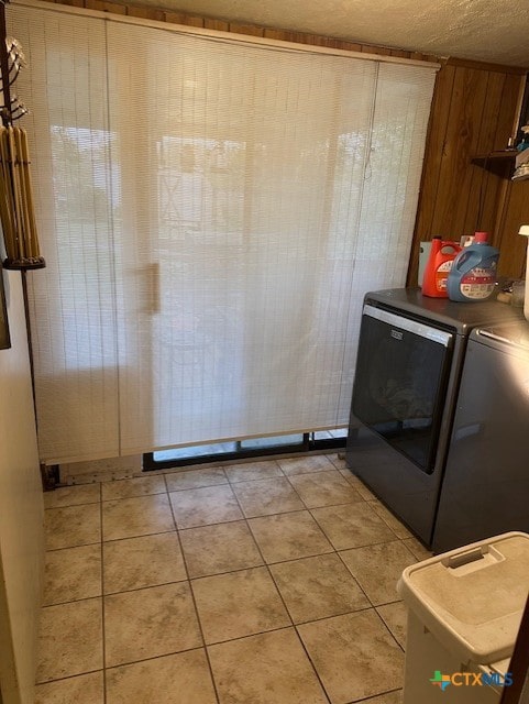 laundry area with light tile patterned flooring, a textured ceiling, washer and dryer, and laundry area