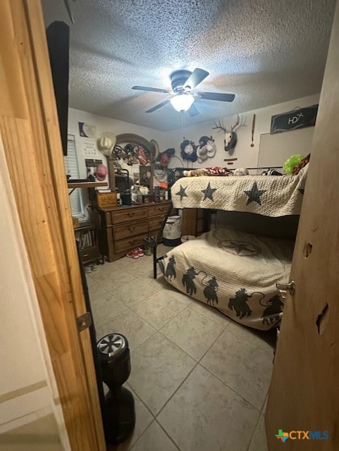 bedroom with a ceiling fan, tile patterned flooring, and a textured ceiling