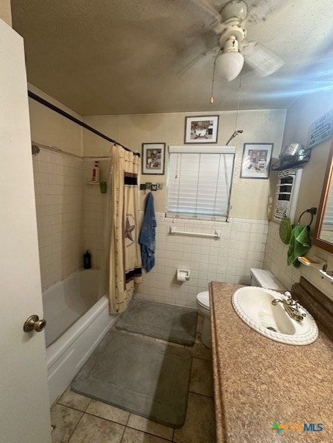 bathroom with a ceiling fan, tile patterned floors, vanity, tile walls, and toilet