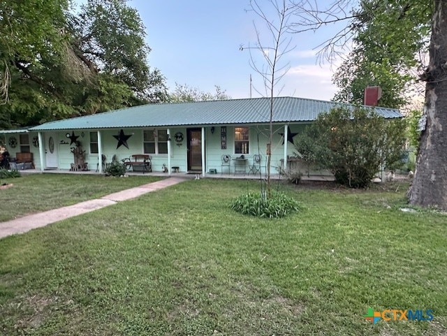 view of front facade featuring a porch, a front lawn, a chimney, and metal roof