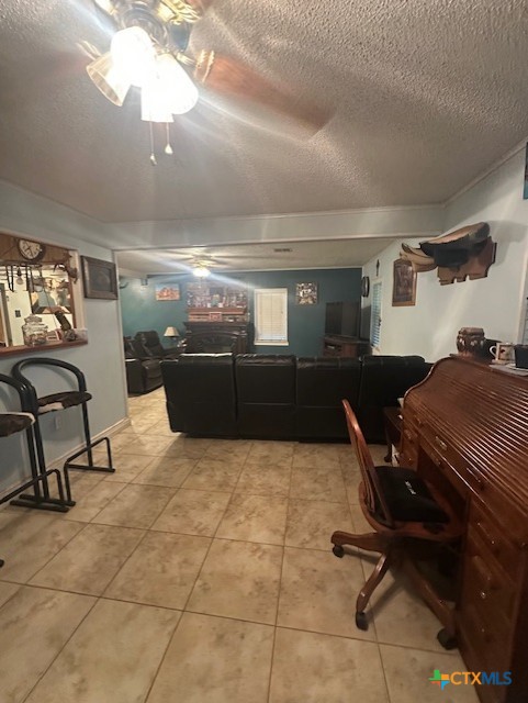 living area with a ceiling fan, a textured ceiling, and light tile patterned floors