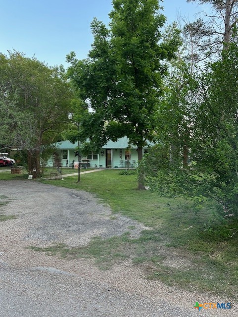 view of front of property with gravel driveway, a front yard, and covered porch