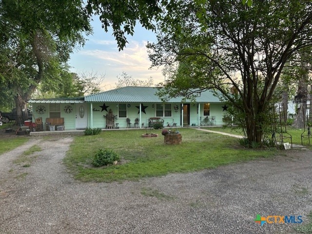 view of front of property with a front lawn, driveway, covered porch, and metal roof