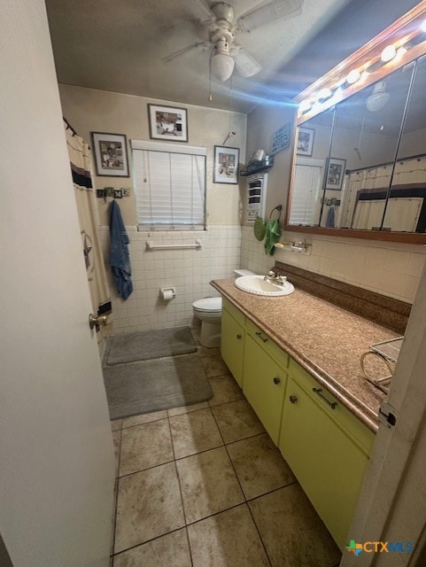 full bathroom featuring tile patterned floors, toilet, tile walls, a ceiling fan, and vanity
