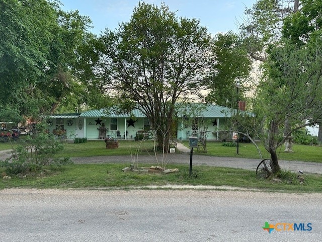 view of front facade with a front lawn, dirt driveway, and covered porch
