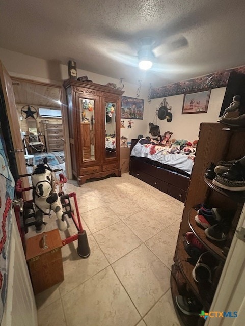 bedroom featuring a ceiling fan, light tile patterned flooring, and a textured ceiling