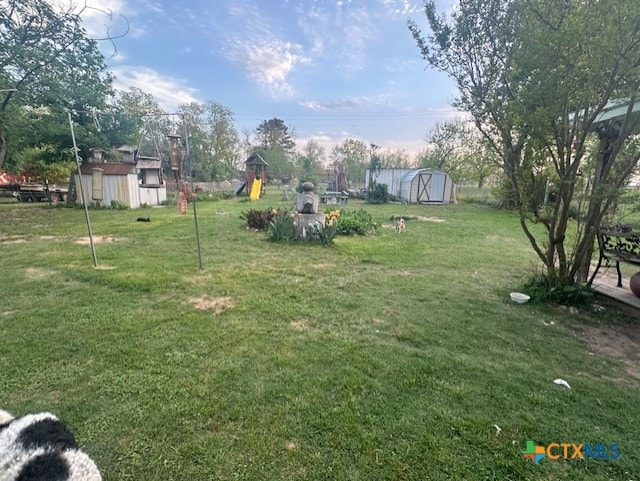 view of yard featuring an outdoor structure, a playground, and a storage unit