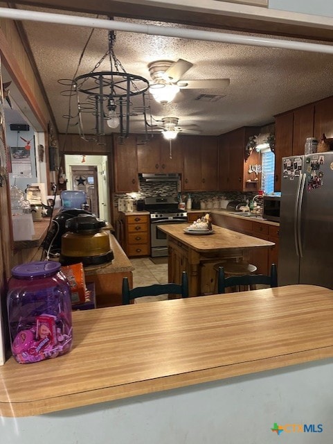 kitchen featuring ventilation hood, stainless steel appliances, visible vents, a textured ceiling, and ceiling fan
