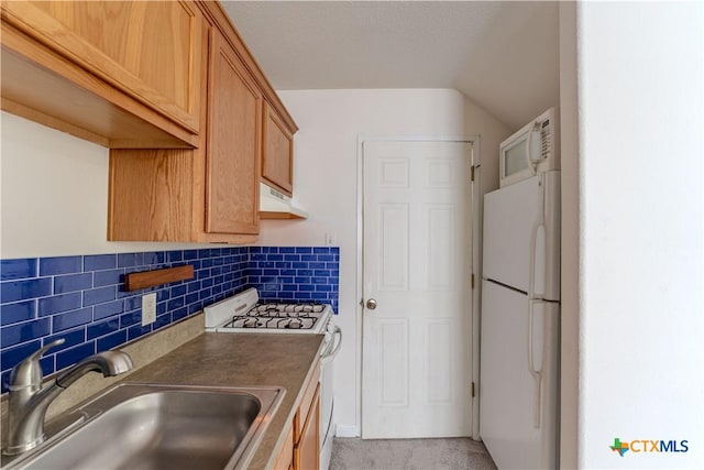 kitchen featuring tasteful backsplash, gas stove, sink, white fridge, and lofted ceiling