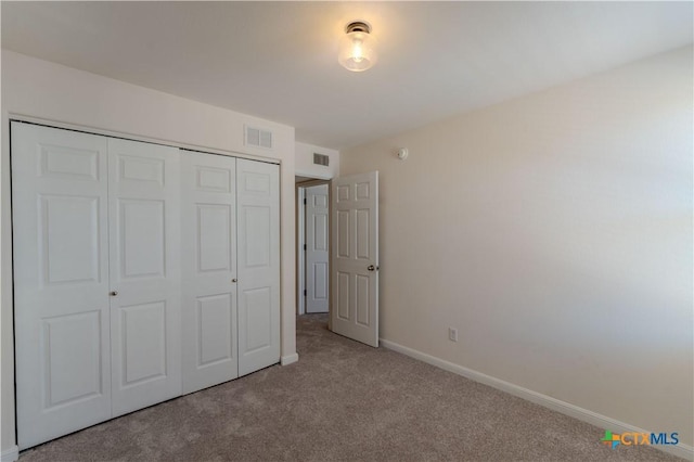 unfurnished bedroom with light colored carpet and a closet