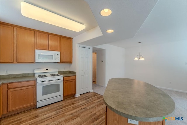 kitchen with light wood-type flooring, white appliances, hanging light fixtures, and a chandelier