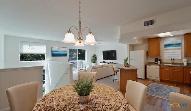 dining area with light hardwood / wood-style flooring, a notable chandelier, and sink