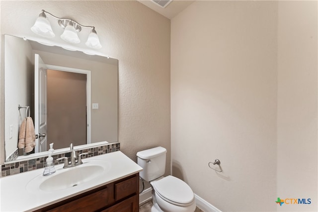 bathroom featuring toilet, backsplash, and vanity