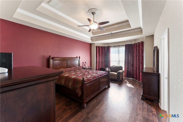 bedroom featuring dark wood-type flooring, a tray ceiling, and ceiling fan