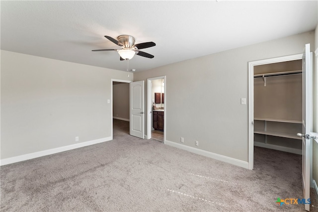 unfurnished bedroom featuring connected bathroom, a closet, a walk in closet, and ceiling fan