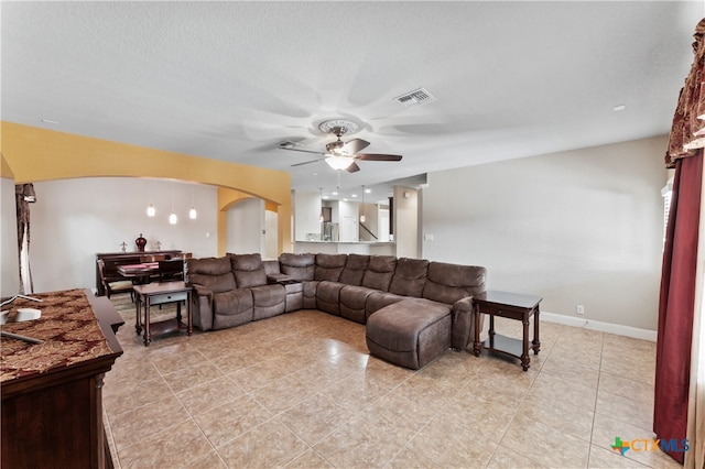 living room featuring ceiling fan, a textured ceiling, and light tile patterned floors