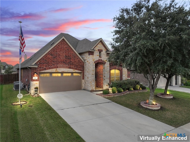 view of front of home featuring central AC, a garage, and a yard