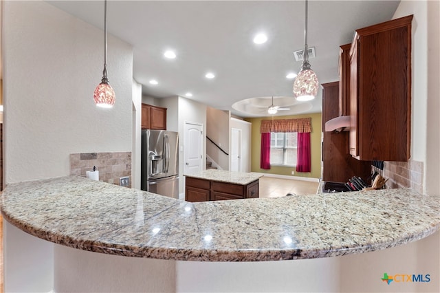 kitchen with kitchen peninsula, stainless steel fridge, pendant lighting, and decorative backsplash