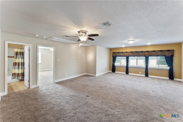 empty room featuring a textured ceiling, light carpet, and ceiling fan