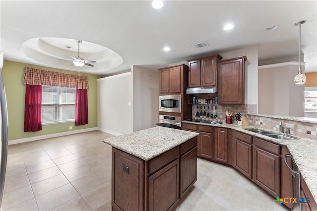 kitchen featuring stainless steel appliances, sink, backsplash, decorative light fixtures, and a raised ceiling