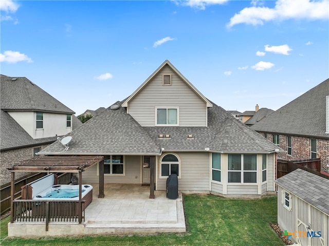 back of property with a hot tub, a lawn, and a patio