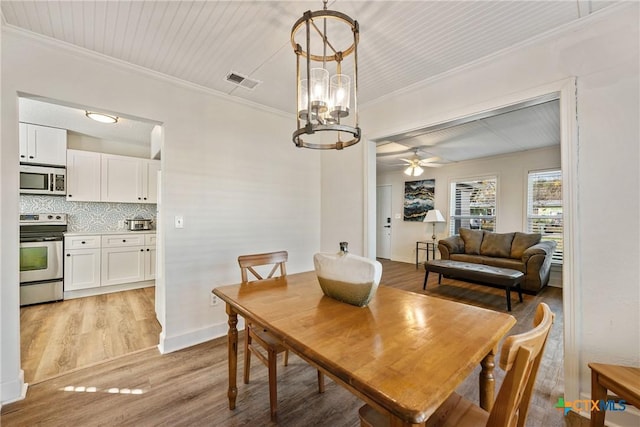 dining area with ceiling fan with notable chandelier, light wood-type flooring, and ornamental molding