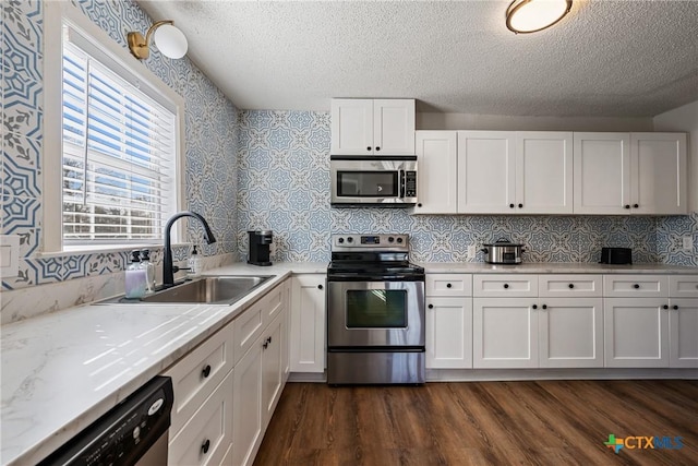 kitchen with sink, stainless steel appliances, dark hardwood / wood-style flooring, a textured ceiling, and white cabinets