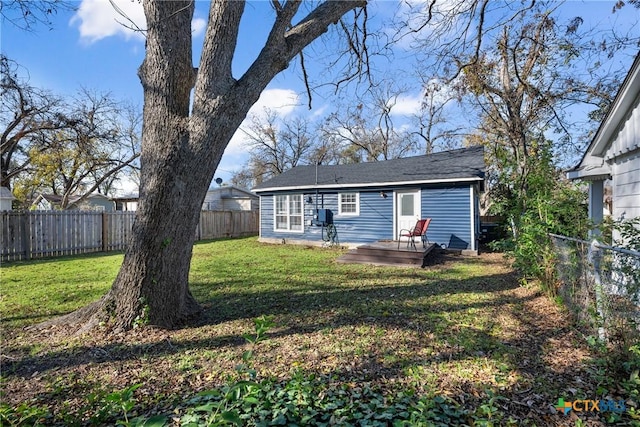 back of property with a deck and a yard