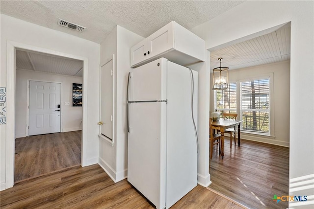 kitchen featuring white cabinets, white refrigerator, hardwood / wood-style flooring, and a chandelier