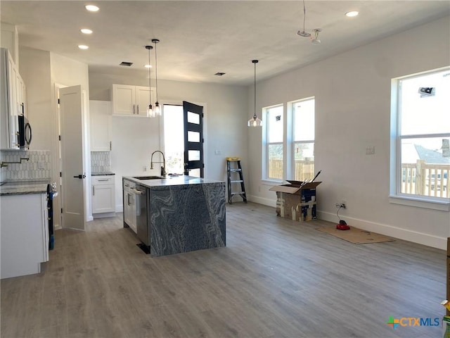 kitchen with sink, white cabinets, dark stone counters, and decorative light fixtures