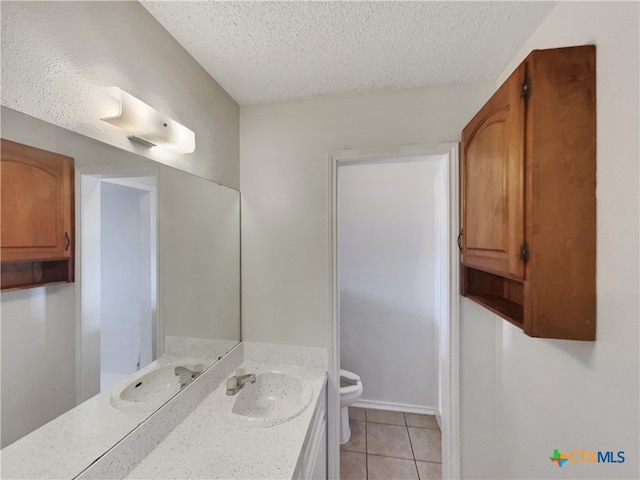 bathroom with toilet, vanity, a textured ceiling, and tile patterned floors