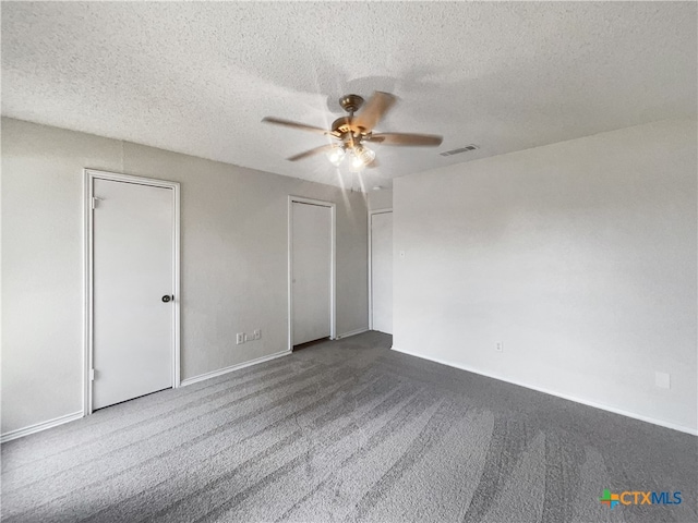 spare room featuring ceiling fan, a textured ceiling, and dark carpet