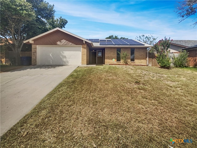 ranch-style house with a front lawn, a garage, and solar panels