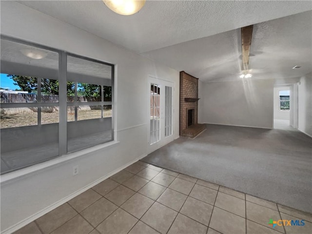 1009 N 4th St, Copperas Cove, TX 76522 - tiled empty room featuring carpet floors, a textured ceiling, a brick fireplace, and a ceiling fan
