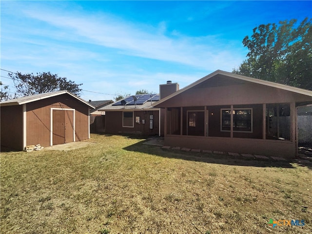 rear view of house with a lawn and a storage unit