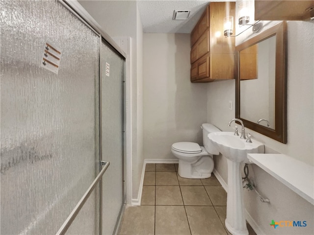 bathroom with a shower with shower door, tile patterned floors, toilet, and a textured ceiling