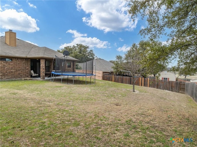 view of yard with a trampoline and a fenced backyard