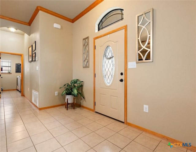 foyer entrance featuring visible vents, arched walkways, crown molding, and light tile patterned flooring