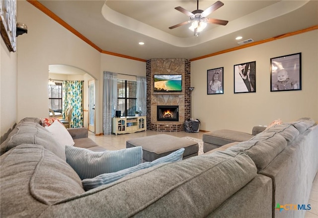 tiled living area with ornamental molding, a fireplace, a raised ceiling, and visible vents