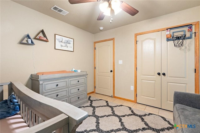 bedroom with a closet, visible vents, light tile patterned flooring, ceiling fan, and baseboards