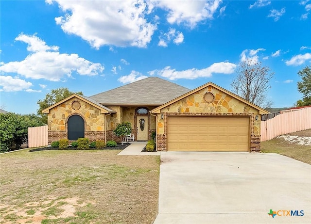 view of front facade with a garage, concrete driveway, fence, and stone siding