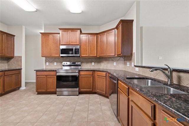 6208 Suellen Ln, Killeen, TX 76542 - kitchen featuring appliances with stainless steel finishes, decorative backsplash, brown cabinetry, dark stone counters, and light tile patterned floors