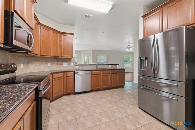6208 Suellen Ln, Killeen, TX 76542 - kitchen with appliances with stainless steel finishes, brown cabinets, backsplash, a ceiling fan, and dark stone countertops