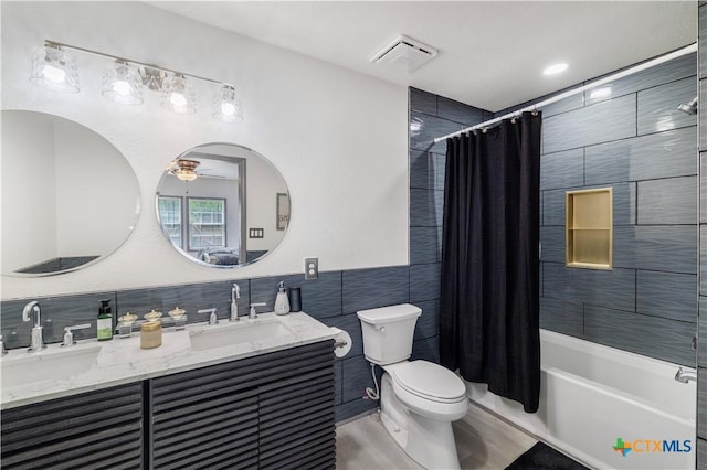full bath with a sink, ceiling fan, tile walls, and visible vents
