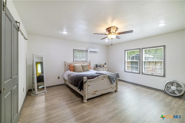 bedroom featuring recessed lighting, a wall mounted AC, a ceiling fan, and light wood-style floors