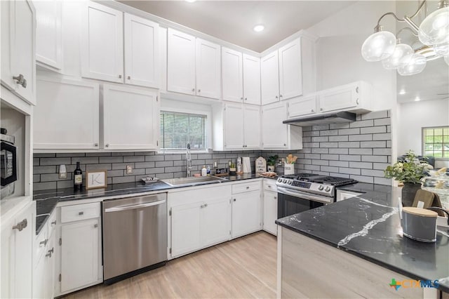 kitchen with a sink, stainless steel appliances, tasteful backsplash, light wood-type flooring, and white cabinetry
