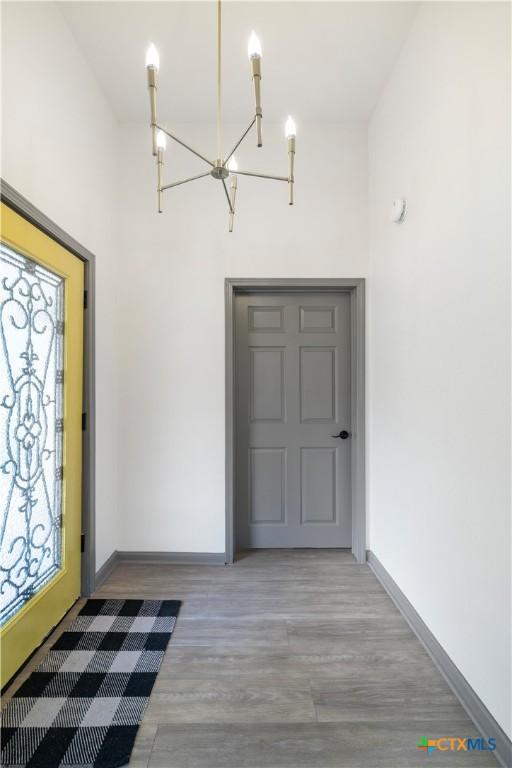 entryway featuring baseboards, an inviting chandelier, and wood finished floors