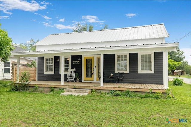 rear view of house featuring a yard, metal roof, and a porch