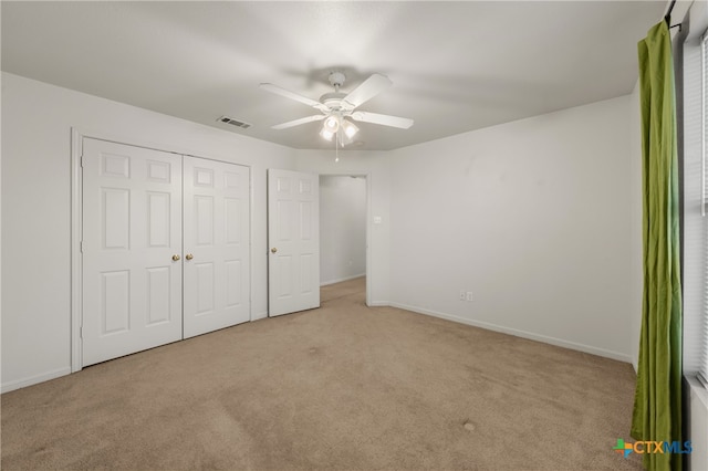 unfurnished bedroom featuring ceiling fan, a closet, and light colored carpet